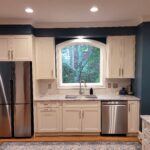 white kitchen with blue walls and stainless steel appliances