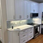 matte light-blue tile backsplash laid in a herringbone pattern with border pieces