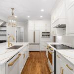 Bright, modern kitchen with white cabinets, gold hardware, and a central island.